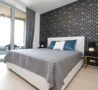 Schlafzimmer mit Bett, Tapete und Zugang zum Balkon in einer 2-Zimmer-Wohnung.