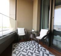 Balkon in einer 2-Zimmer-Wohnung mit Rattanmöbeln und Blick auf die Stadt.