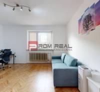 Ein Zimmer in einem Einfamilienhaus mit einem Schreibtisch, einem Sofa und einem Boden mit Holzdekor.
