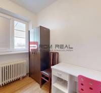 Ein Zimmer in einem Einfamilienhaus mit einem weißen Tisch, einem undurchsichtigen Stuhl und einem Schrank.