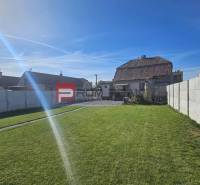 Der Garten des Einfamilienhauses in der Kroatische Straße in Slowakisch Grob mit Rasen und Zaun.