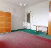 Ein Zimmer in einem Einfamilienhaus mit Teppichen, zwei Schränken und einem Tisch.