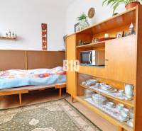 Ein Zimmer in einem Einfamilienhaus mit einem Bett, einer Vitrine und einem Boden mit Holzdekor.