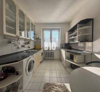 Küche in einer 2-Zimmer-Wohnung mit weißen Schränken und schwarzer Arbeitsplatte.