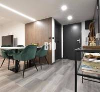 Innenraum einer 4-Zimmer-Wohnung mit Holzboden, Esstisch und grünen Stühlen.