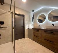 Badezimmer in einer 4-Zimmer-Wohnung mit zwei ovalen Spiegeln und einer Duschkabine.