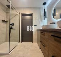 Badezimmer in einer 4-Zimmer-Wohnung mit offener Dusche und Boden in Holzoptik.