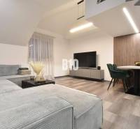 Wohnzimmer in einer 4-Zimmer-Wohnung mit Sofa, Fernseher und Holzboden.