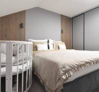 Schlafzimmer mit Bett, Kinderbett, Holzelementen und neutralen Farben in einer 4-Zimmer-Wohnung.