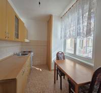 Küche mit Holzschränken, Tisch und zwei Stühlen in einer 3-Zimmer-Wohnung.