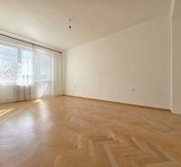 Ein geräumiges Zimmer mit großen Fenstern und einem Boden in Holzoptik in einer 3-Zimmer-Wohnung.