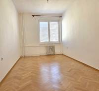 Ein leerer Raum mit Holzboden in einer 3-Zimmer-Wohnung, helle Wände, Heizkörper.