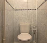 Toilette mit weißen Keramikfliesen in einer 3-Zimmer-Wohnung.