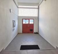 Ein Flur mit Fliesen, der zu einer roten Tür in einer 3-Zimmer-Wohnung führt.