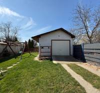 Ein Einfamilienhaus in Zlaté Moravce mit Rasen, Schaukel und Garage auf dem Grundstück.