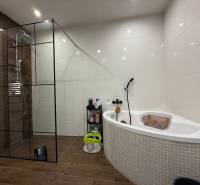 Ein Badezimmer in einem Einfamilienhaus mit Eckbadewanne und Duschkabine, Boden mit Holzdekor.