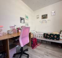 Kinderzimmer mit Schreibtisch, rosa Stuhl und Bett mit Dekor für ein Kind.
