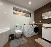 Badezimmer in einem Einfamilienhaus mit Badewanne, Waschmaschine, Trockner und Boden mit Holzdekor.