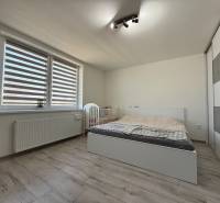 Helles Schlafzimmer in einem Einfamilienhaus mit Bett, Kleiderschrank und Boden in Holzoptik.
