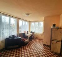 Ein Zimmer in einem Einfamilienhaus mit kariertem Boden, Möbeln und großen Fenstern mit Aussicht.