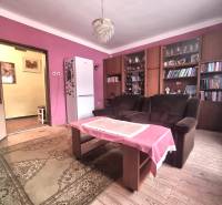 Wohnzimmer eines Einfamilienhauses mit rosa Wänden, Holzboden und Bücherregal.