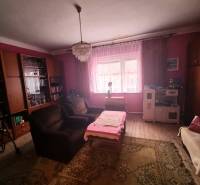 Wohnzimmer eines Einfamilienhauses mit rosa Wänden, Kronleuchter, Sofa und Holzboden-Dekor.