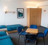 Ein Zimmer mit zwei Betten, blauer Bettwäsche, einem Schrank, einem Tisch und vier Stühlen.