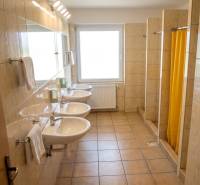 Das Badezimmer im Gebäude bietet Waschbecken und Duschen mit gefliestem Boden.