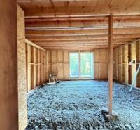 Unvollendetes Interieur einer Hütte mit Holzkonstruktion und einer Öffnung zur Terrasse.