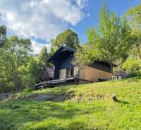 Eine Hütte in Horna Marikova, umgeben von grünen Bäumen an einem sonnigen Hang unter blauem Himmel.