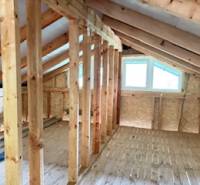 Dachboden mit Fenster, Holzbalken und Holzboden in einer Hütte.