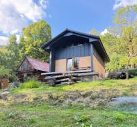 Eine Hütte in Horna Marikova, umgeben von Natur und Holzbauten, an einem sonnigen Tag.
