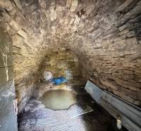 Steinkeller der Hütte mit Gewölbedecke und Metallelementen.