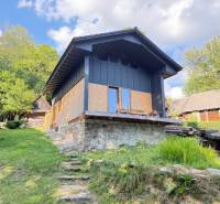Eine Hütte im Dorf Horná Mariková mit steinernem Fundament und umgebender Natur.