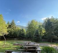 Die Natur in Horná Mariková mit einer Hütte, ein Tisch mit Bänken umgeben von Bäumen und Bergen.