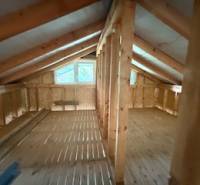 Dachboden eines Chalets mit Holzbalken und einem Boden in Holzoptik.