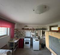 Küche in einem Einfamilienhaus mit einem älteren Herd und leuchtend roten Vorhängen.