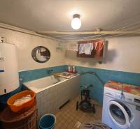 Ein Badezimmer in einem Einfamilienhaus mit einer Badewanne, einer Waschmaschine und einem Boiler, blaue Fliesen.