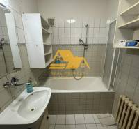 Badezimmer mit Badewanne, Waschbecken, weißen Schränken und Heizkörper in einem Einfamilienhaus.