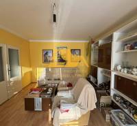 Wohnzimmer in einem Einfamilienhaus mit weißem Sofa, Holzboden, gelbe Wände.