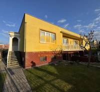 Gelbes Einfamilienhaus in Nové Zámky in einer Straße mit gepflegtem Garten und Gehweg.
