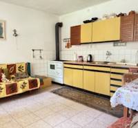 Eine Küche in einem Einfamilienhaus mit beigefarbenen Küchenschränken und einem Kachelofen.