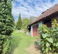 Ein Einfamilienhaus in Krivosúd-Bodovka mit roten Türen und Sonnenblumen im Garten.