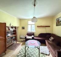 Wohnzimmer mit Teppichen, Büchern, braunem Sofa und Holzboden in einem Einfamilienhaus.