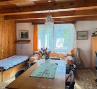 Ein Zimmer in einem Einfamilienhaus mit Holzbalken, einem Esstisch und zwei Betten.