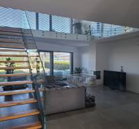 Wohnzimmer in einem Einfamilienhaus mit Treppe und verglasten Geländern.