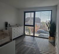 Kinderzimmer in einem Einfamilienhaus mit Kommode, Kinderbett und großem Fenster.