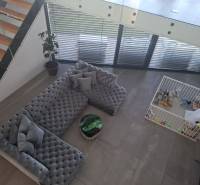 Obývací pokoj v rodinném domě s velkou pohovkou, dětským koutkem a schody.