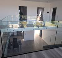 Innenraum eines Einfamilienhauses mit verglastem Geländer und Holzboden.