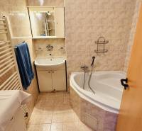 Das Badezimmer einer 3-Zimmer-Wohnung mit Badewanne, Waschbecken und beigen Fliesen.